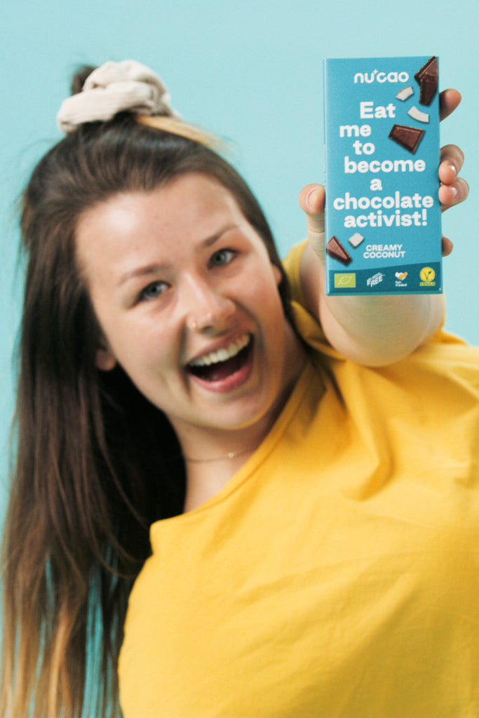 Frau hält die nucao Tafelschokolade in der Sorte Creamy Coconut in die Kamera.